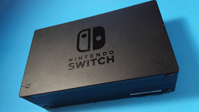 The Nintendo Switch dock on its side against a blue background