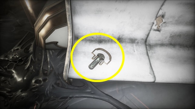 Warframe screenshot of an amulet resting on a chair with a yellow circle around it