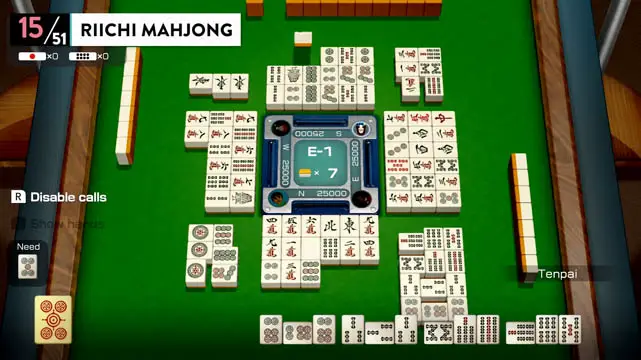 A riichi mahjong table filled with game pieces atop a green tabletop