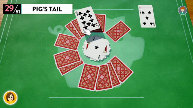 Playing cards set upside down in a circle atop a green tabletop in a game of Pig's Tail