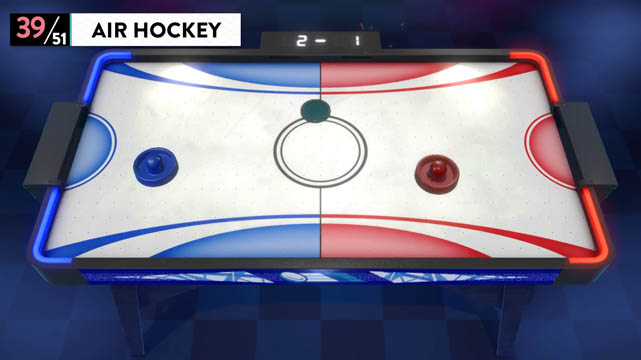 An air hockey table with red and blue paddles and a green puck