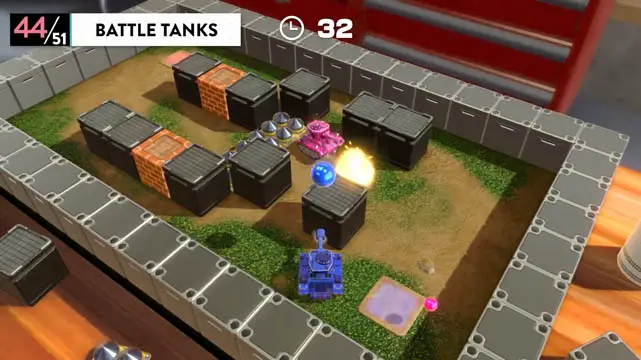 An overhead view of two toy tanks battling each other in a mini battlefield filled with crates