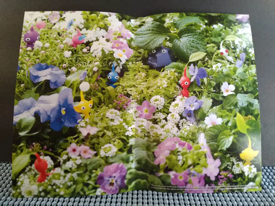 Close-up of Pikmin 3 Deluxe's reversible cover: a green forest setting with Pikmin creatures resting in greenery