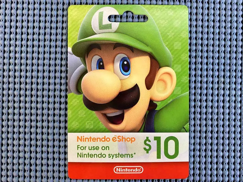 A close-up of a Nintendo eShop gift card on a table with Luigi artwork