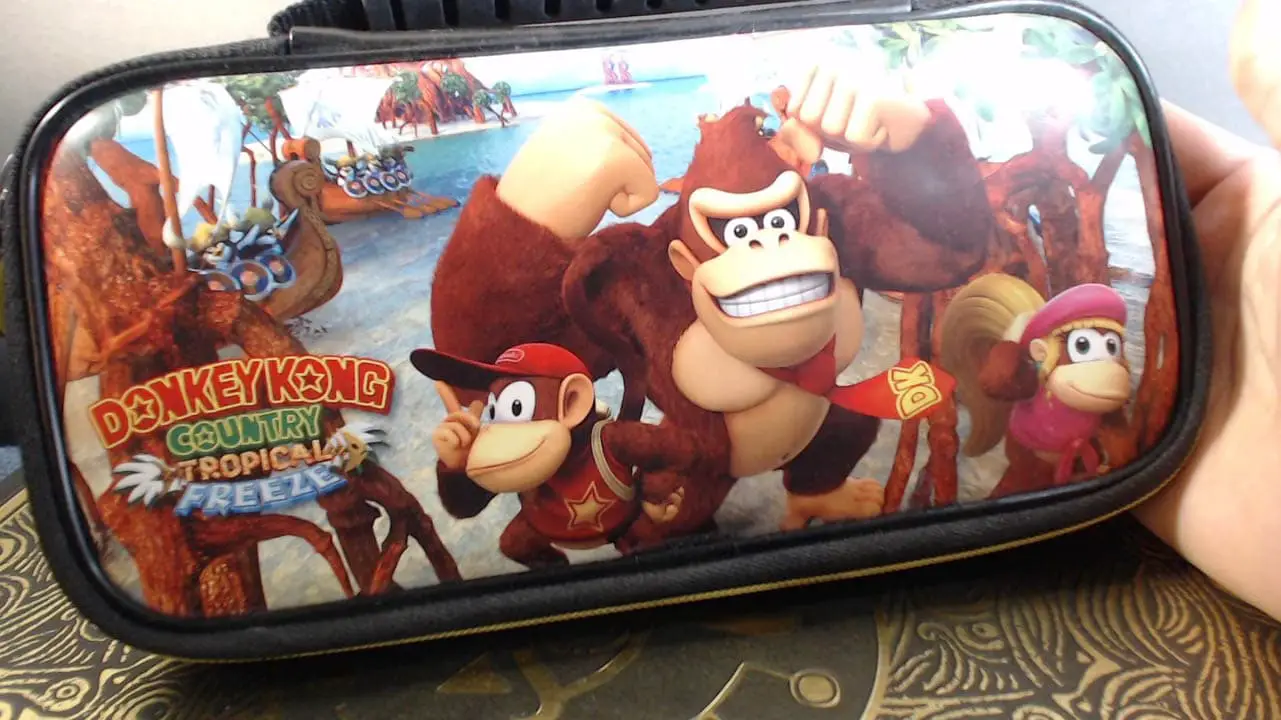 A hand holding a Donkey Kong themed Nintendo Switch carrying case