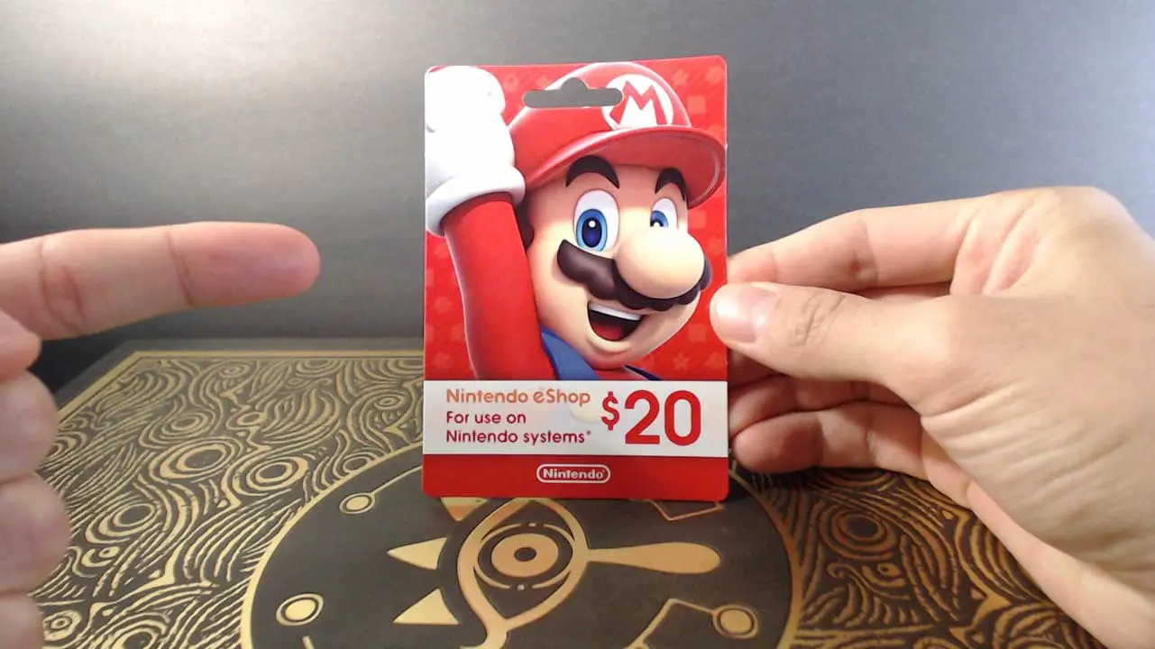 A hand holding a red mario Nintendo gift card