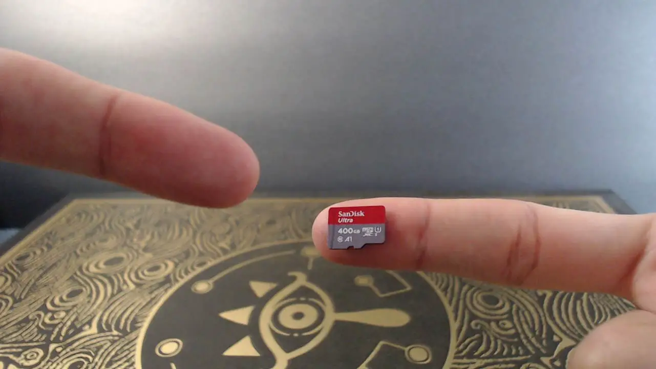 A microSD card on a finger with a finger pointing at it