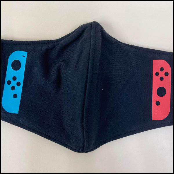 A face mask; black with blue and red Joy COn controller art oen on each end