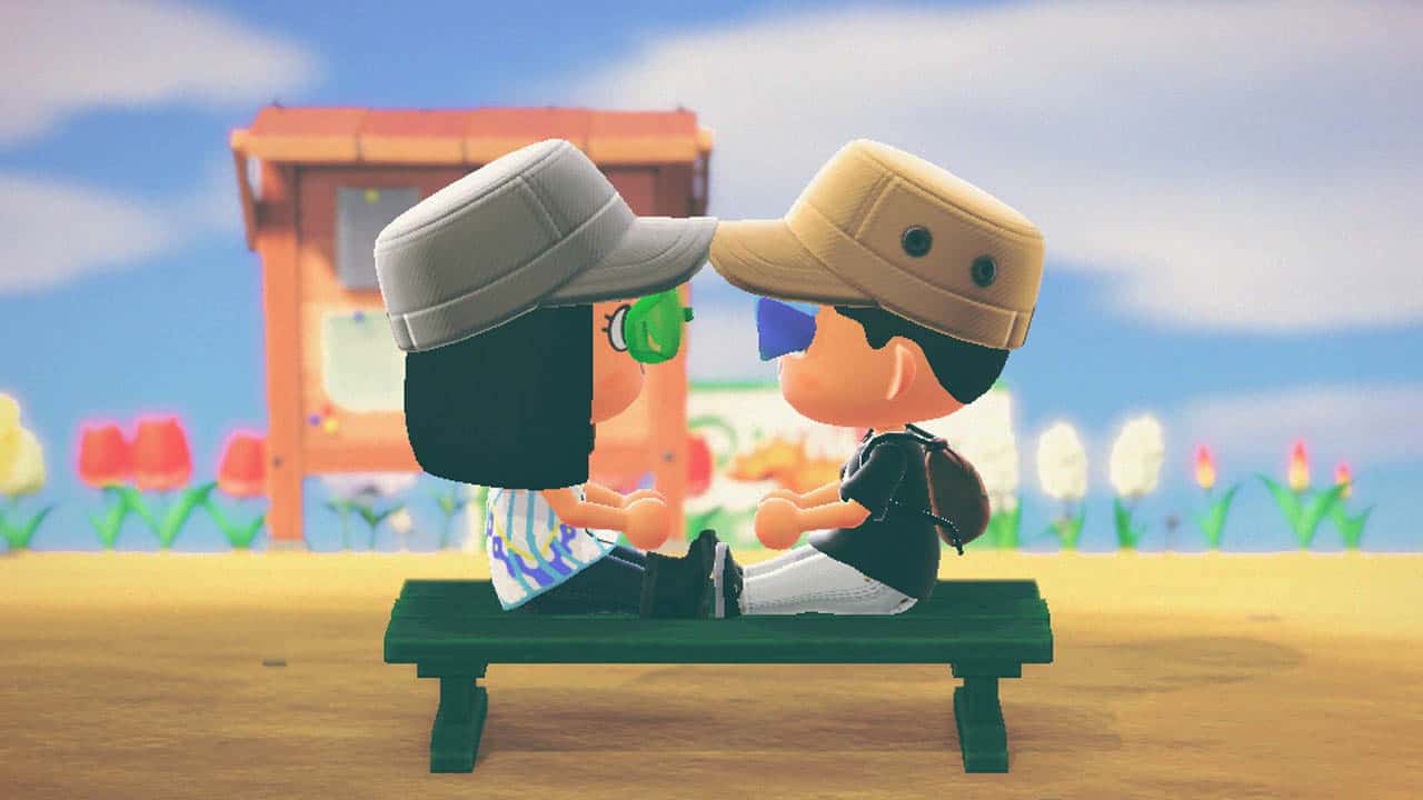 Two people sitting on a bench looking at each other wearing hats in the day time