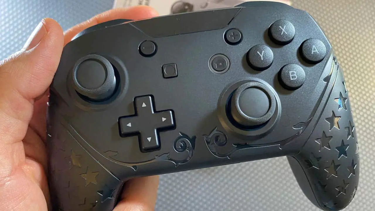 Close up of a hand holding a black wireless nintendo switch controller